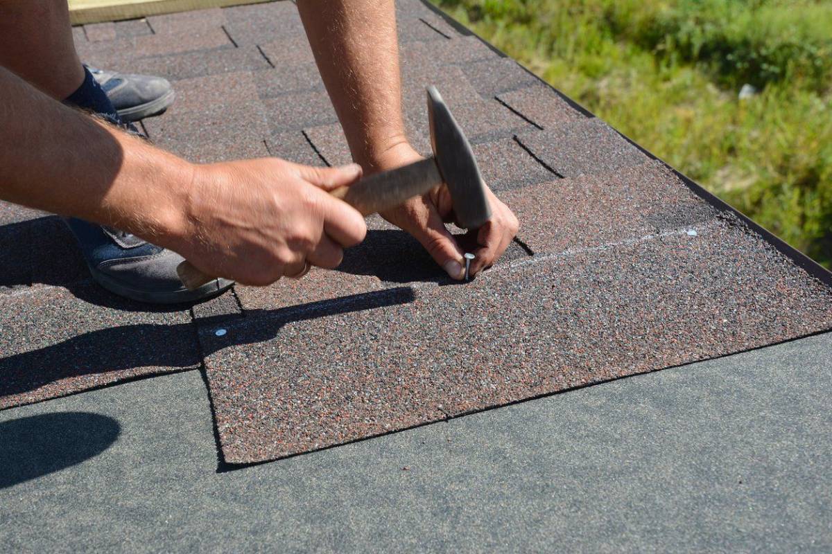 Professional repairing damaged roof shingles